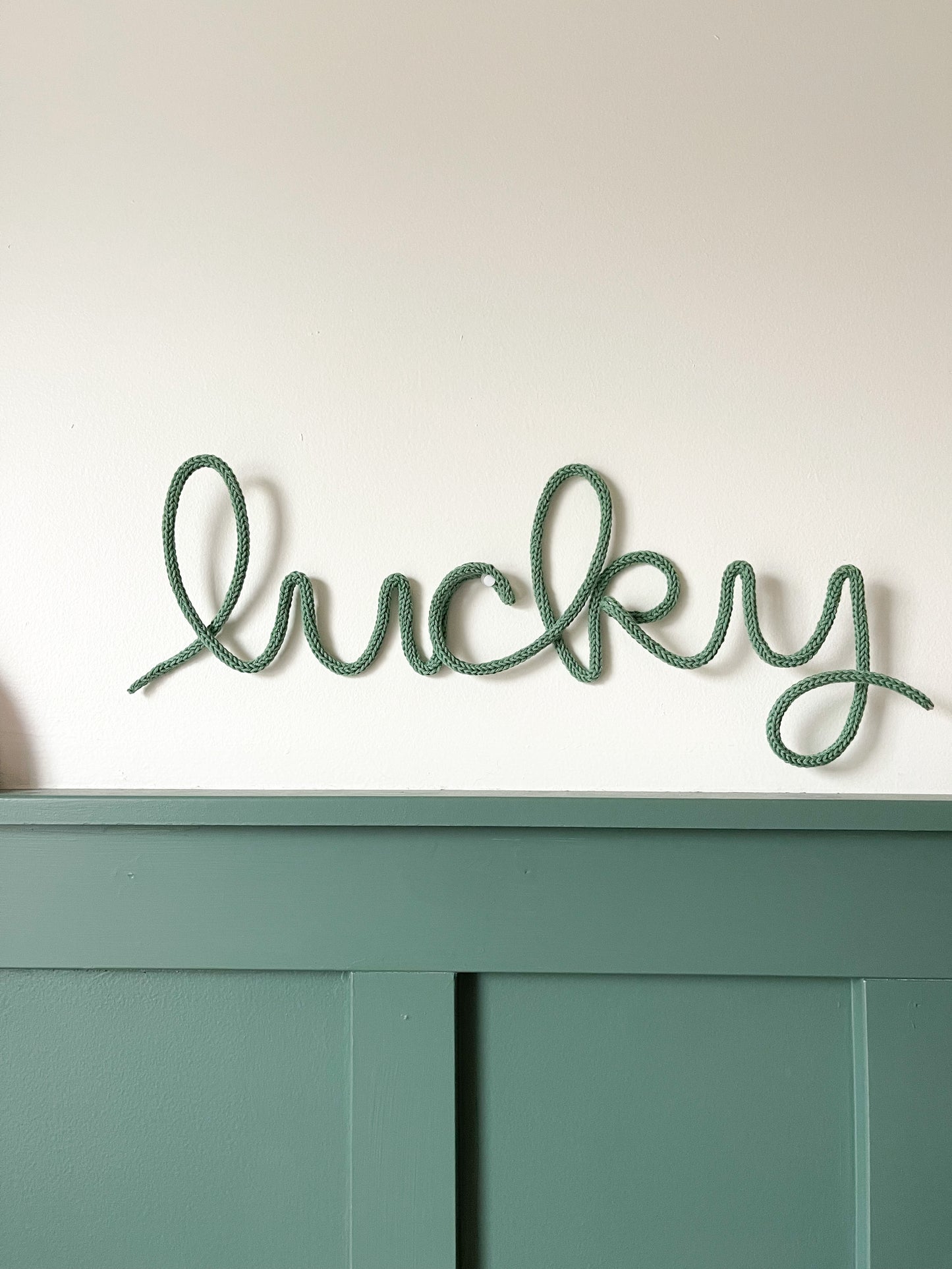 Knitted wire word lucky. It's displayed in a child's room over their desk.