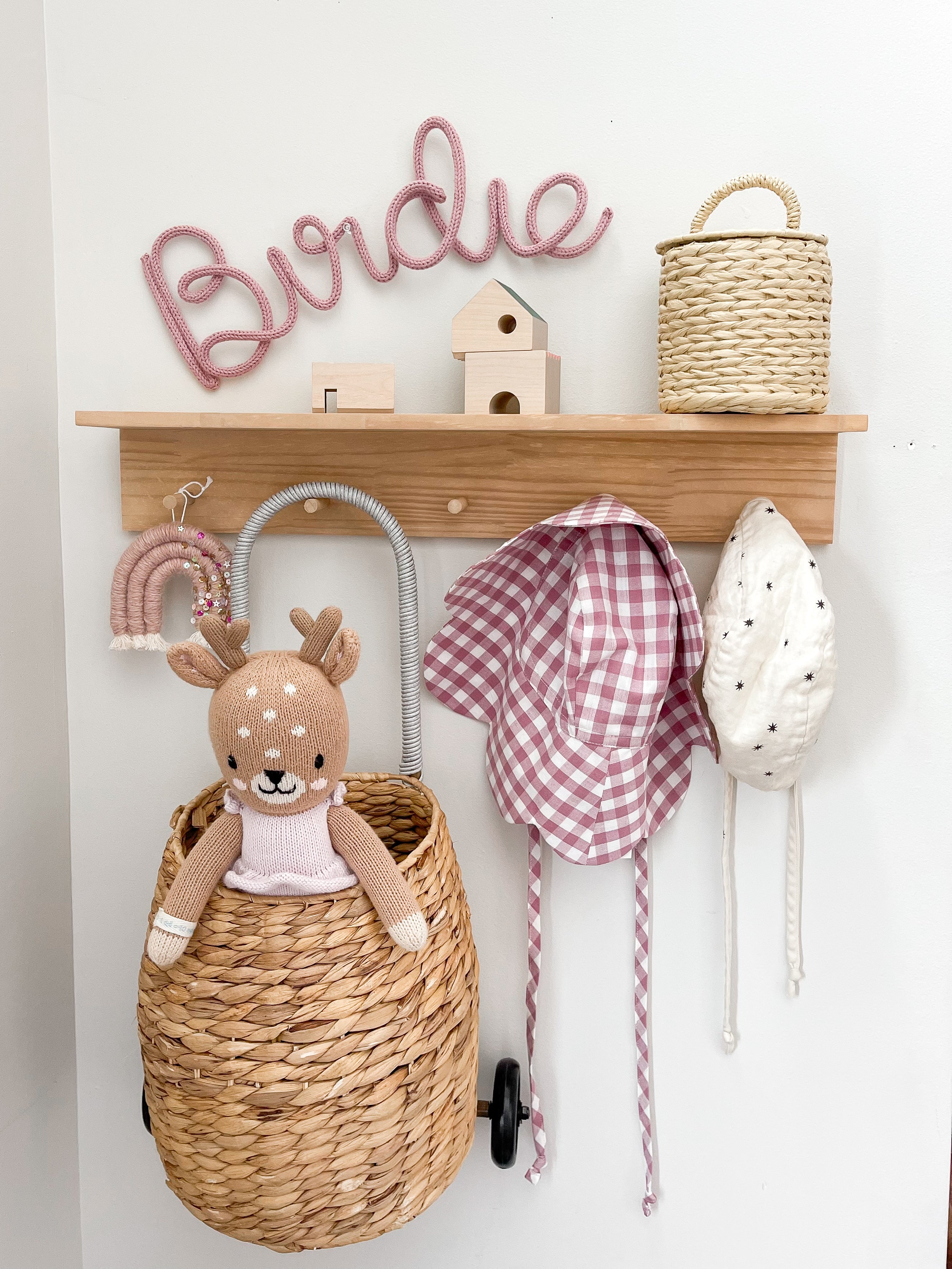 Children's room with wooden shelf, wicker basket, stuffed deer toy, and decorative items.