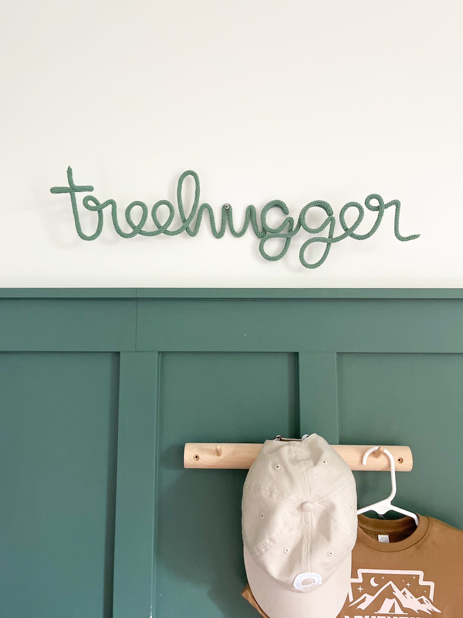 Knitted wire word treehugger hung on a child's bedroom wall. IThe room is nature inspired and outdoorsy.