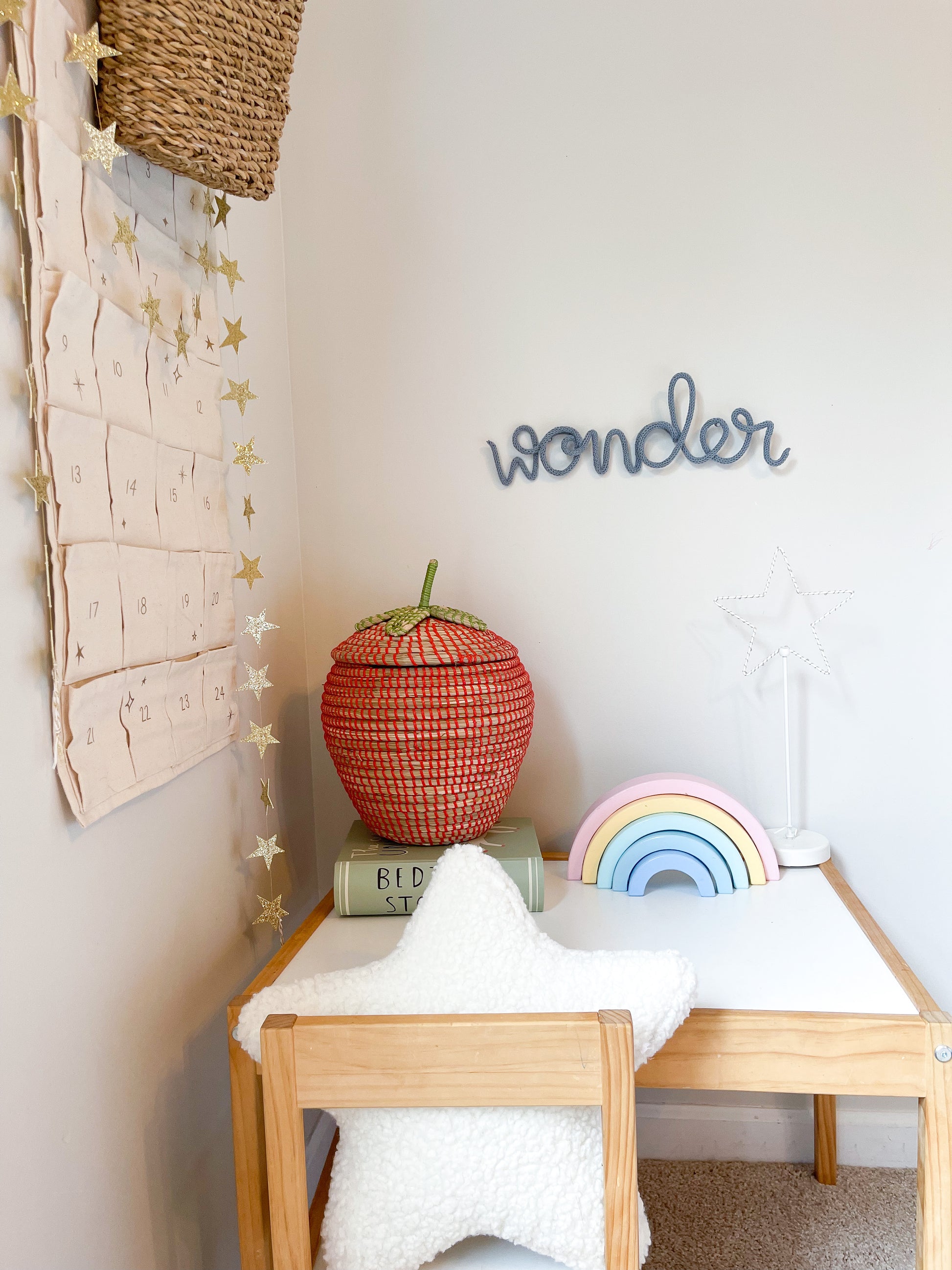 Knitted wire word "wonder" styled in corner of kid's room. It's hung above a desk.