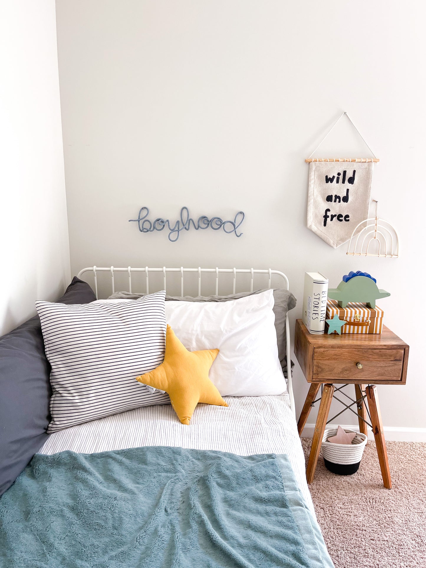 Knitted wire word "boyhood" sign hanging above boys bed.