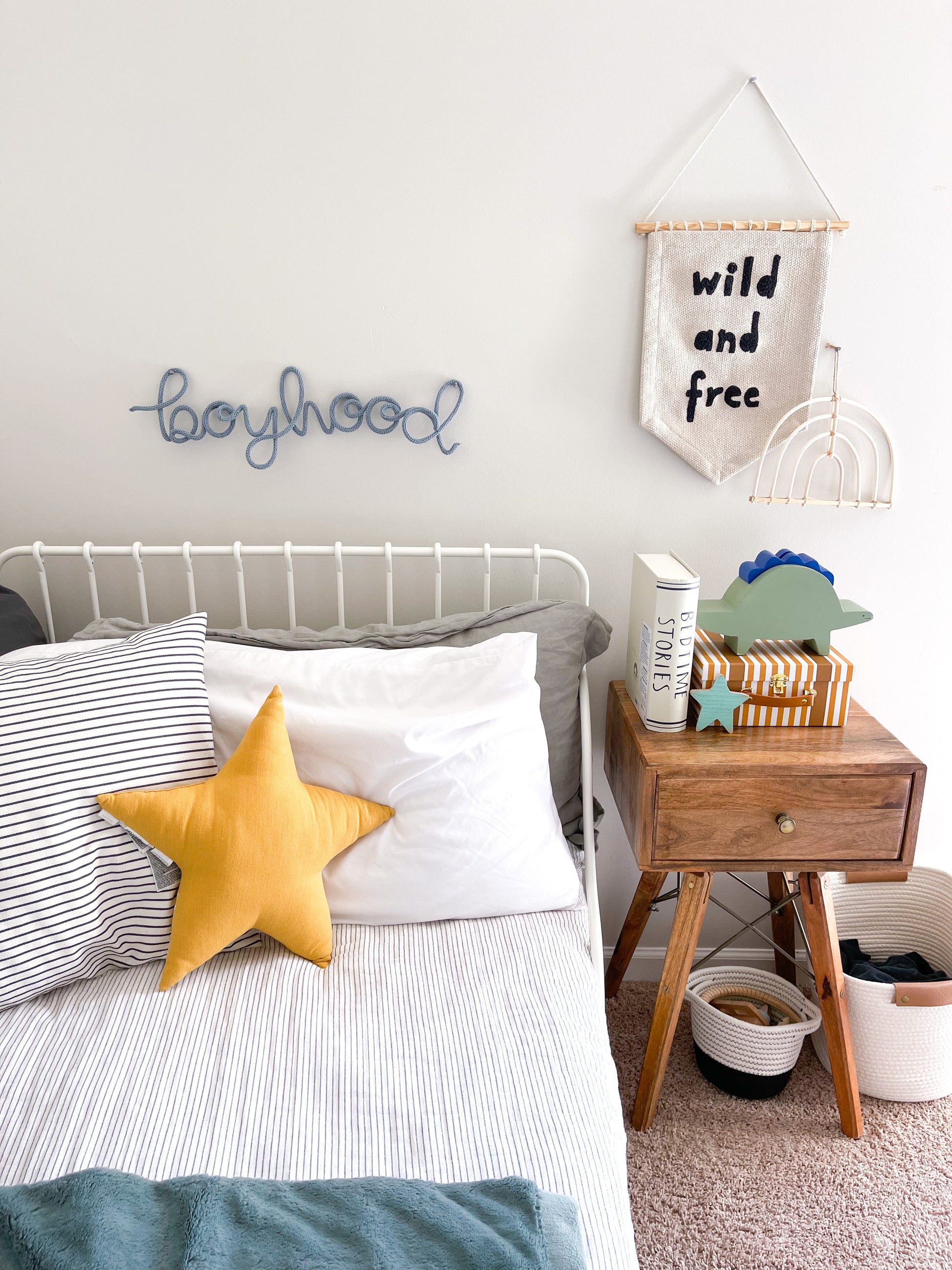 Knitted wire word "boyhood" sign hanging above boys bed.