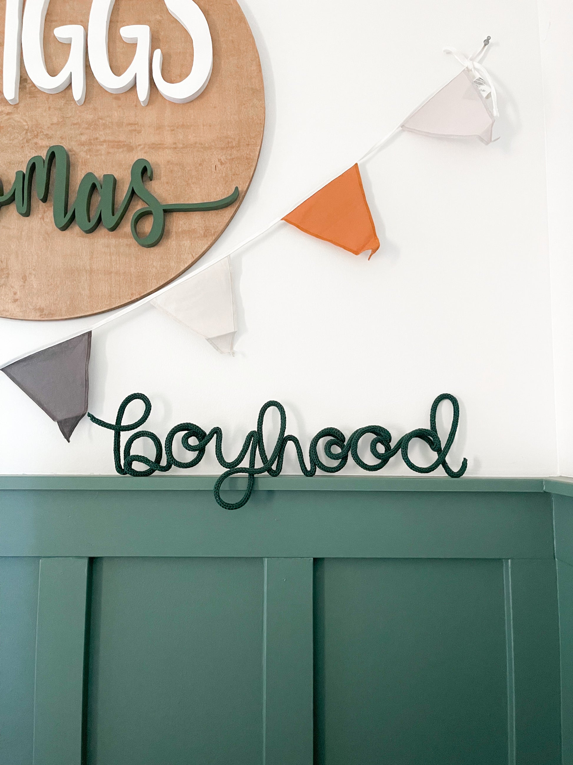 Knitted wire word "boyhood" propped up on ledge of boys room. 
