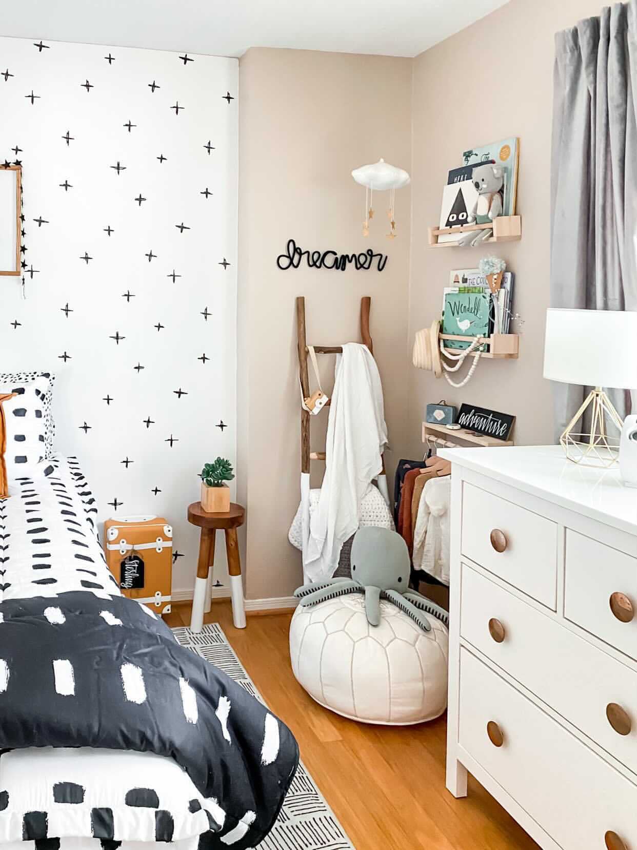 Knitted wire word "dreamer" in black. It's styled in a child's bedroom corner with some bookshelves. The style of the room is scandinavian inspired with lots of black and white, graphic patterns and natural wood tones.