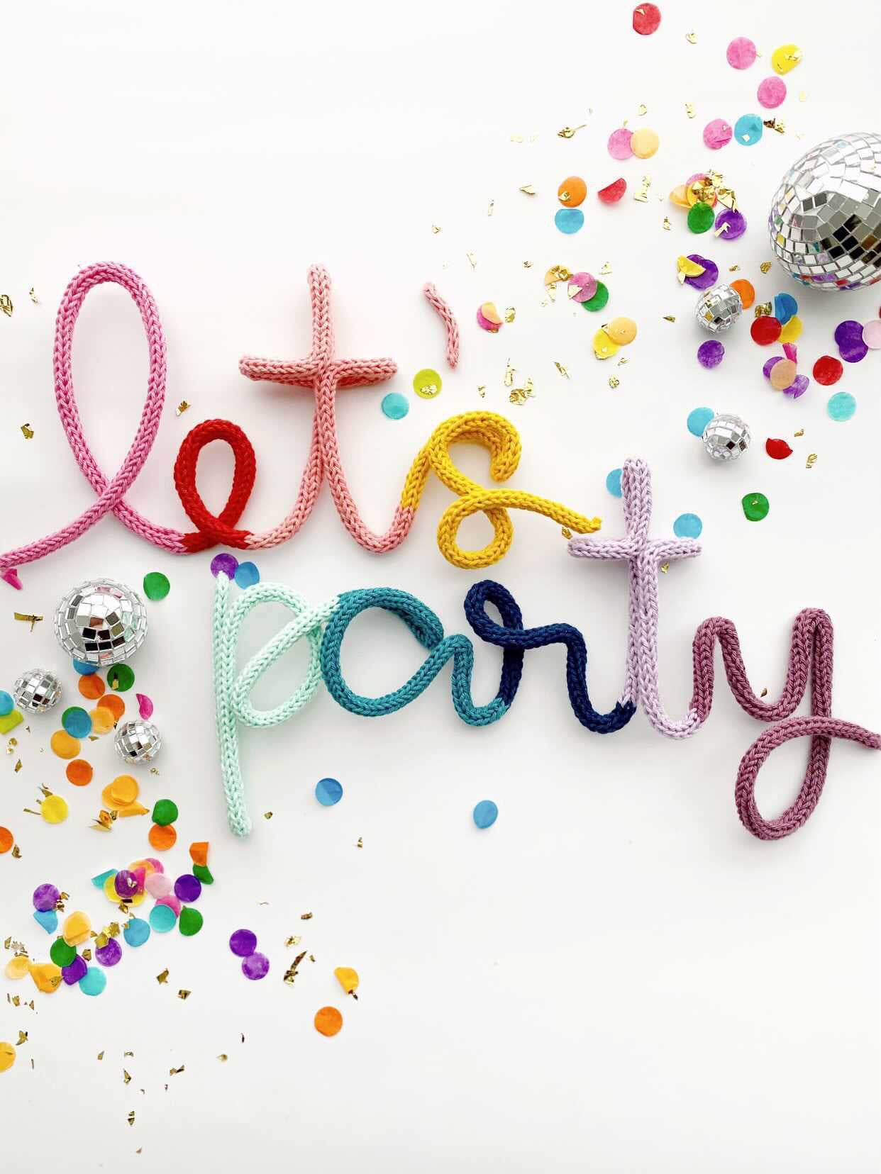 Knitted wire word "let's party" in rainbow color scheme.