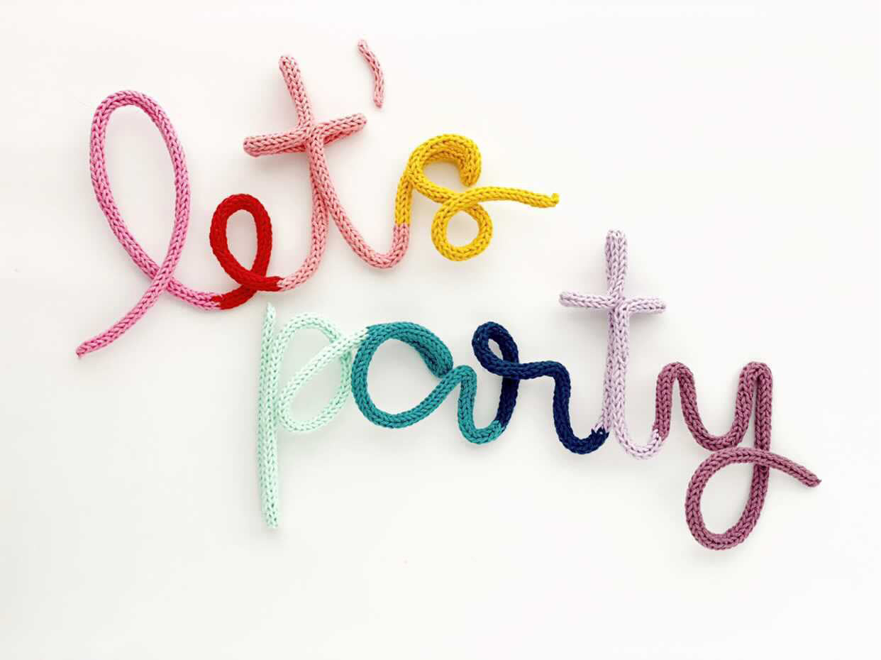 Knitted wire word "let's party" in rainbow color scheme.