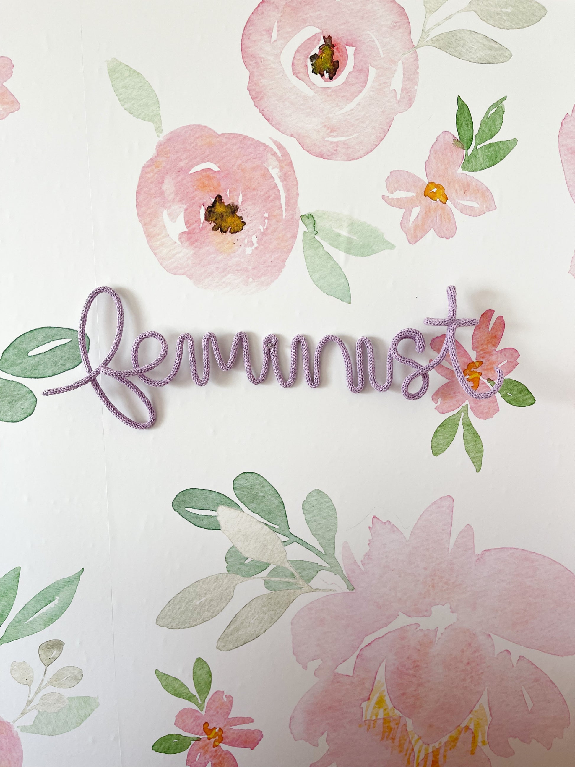 Knitted wire word "feminist" sign hung in a little girl's bedroom.