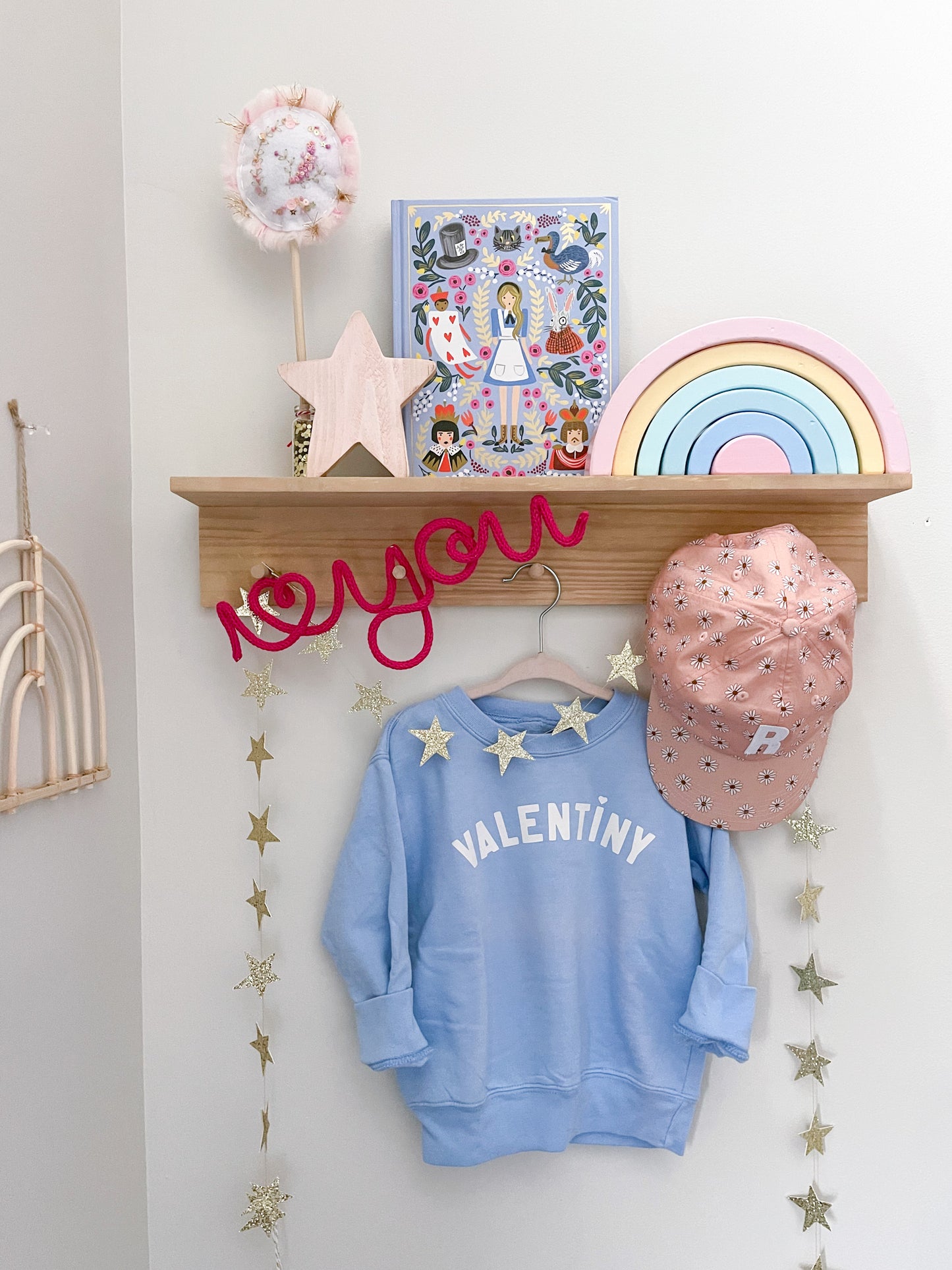 Knitted wire art "i heart you" sign featuring a vibrant neon pink color hanging on a styled peg rail in a kid's room.