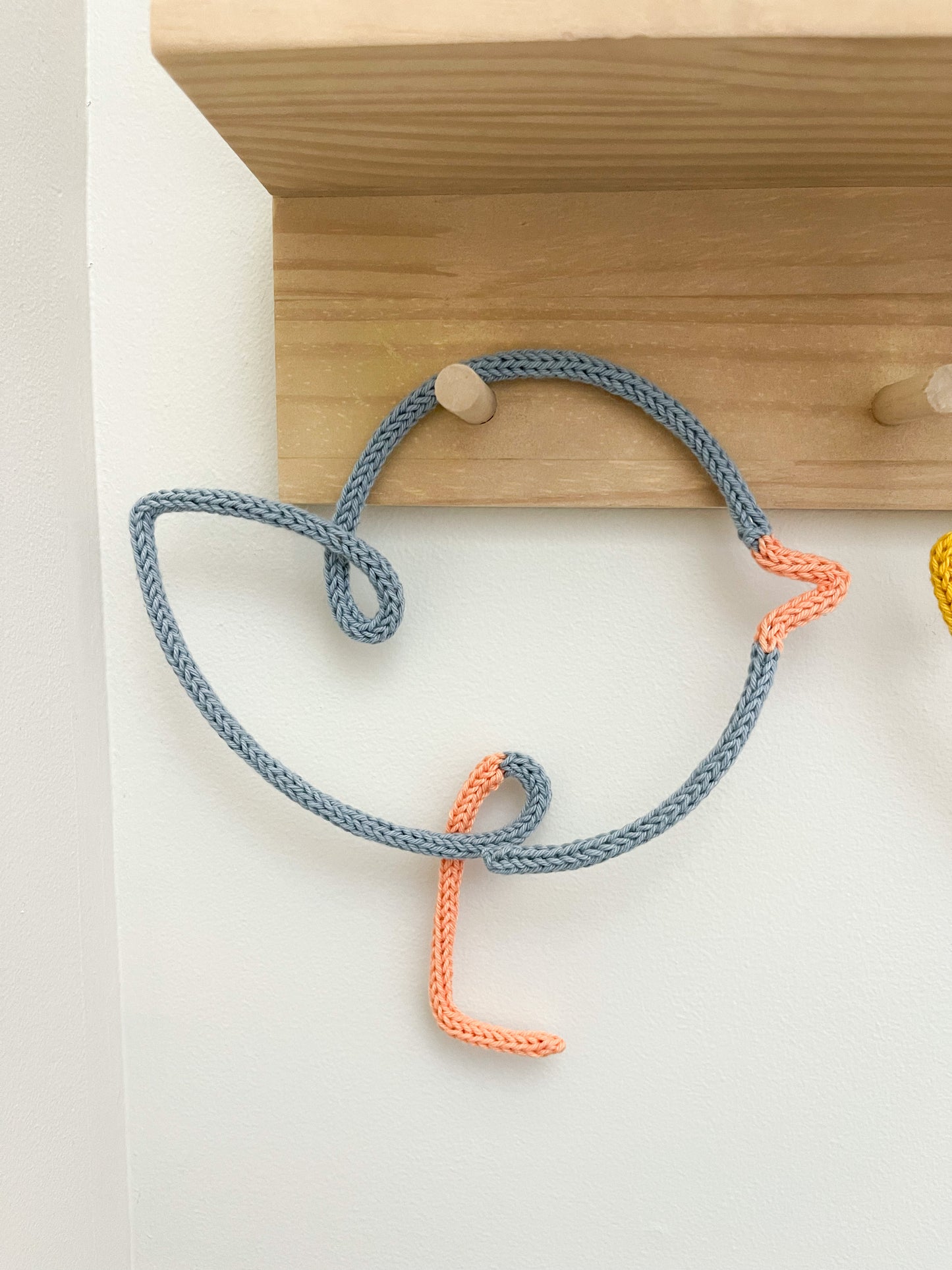 Knitted wire art shaped chicks on peg rail shelf.