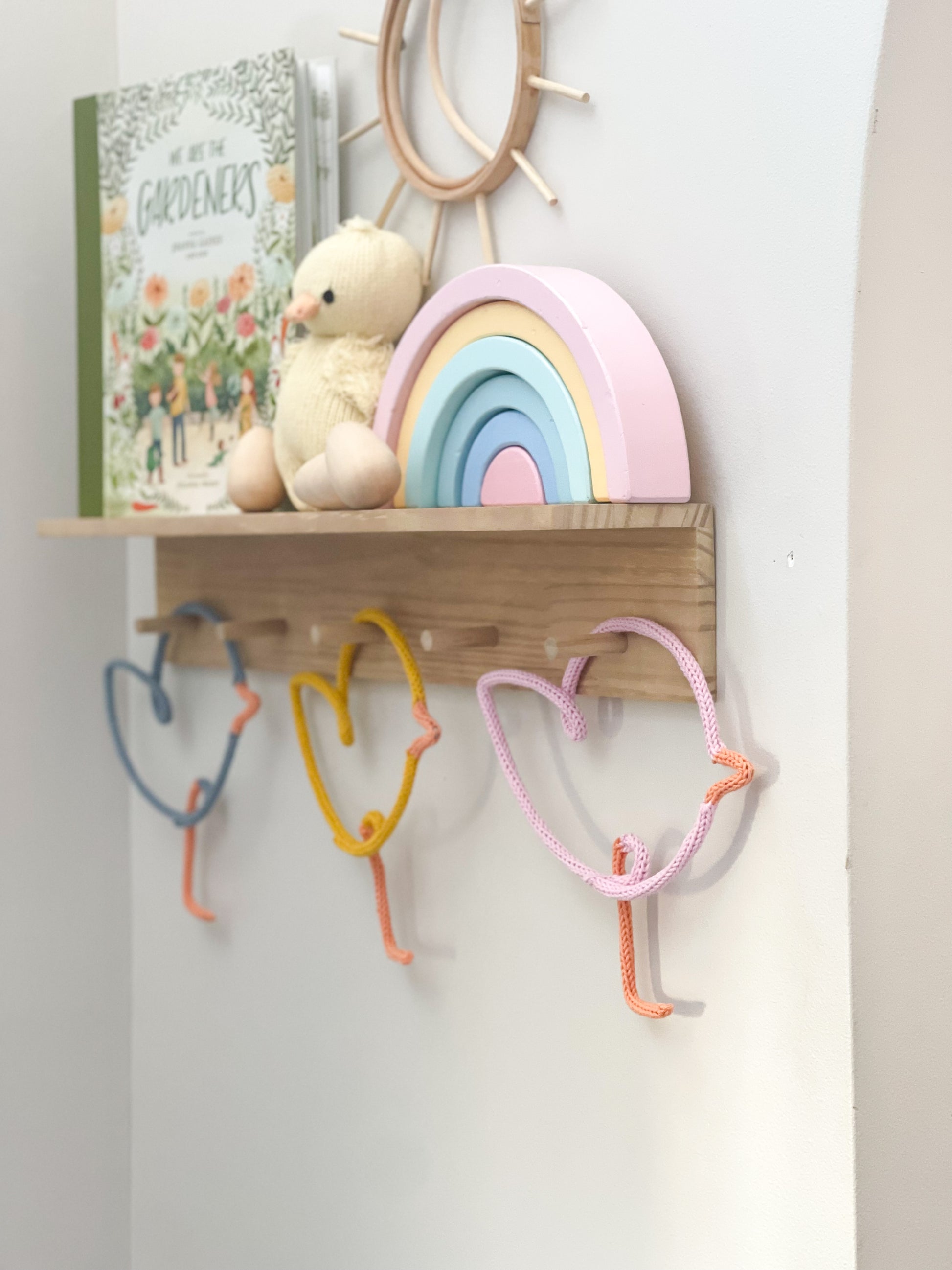 Knitted wire art shaped chicks on peg rail shelf.