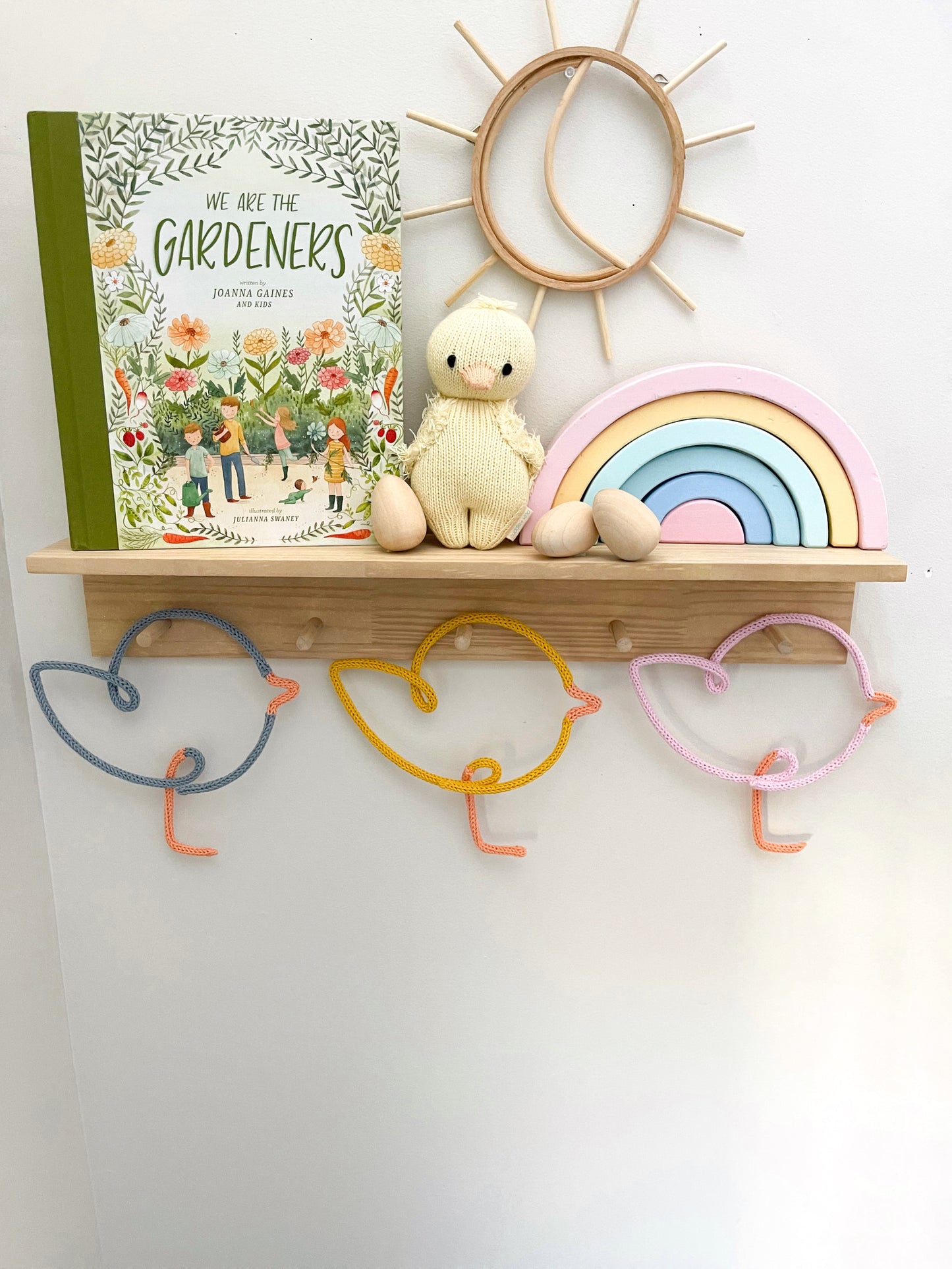 Knitted wire art shaped chicks on peg rail shelf.