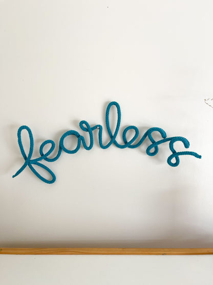 Knitted wire word "fearless". Hung above child's desk. 