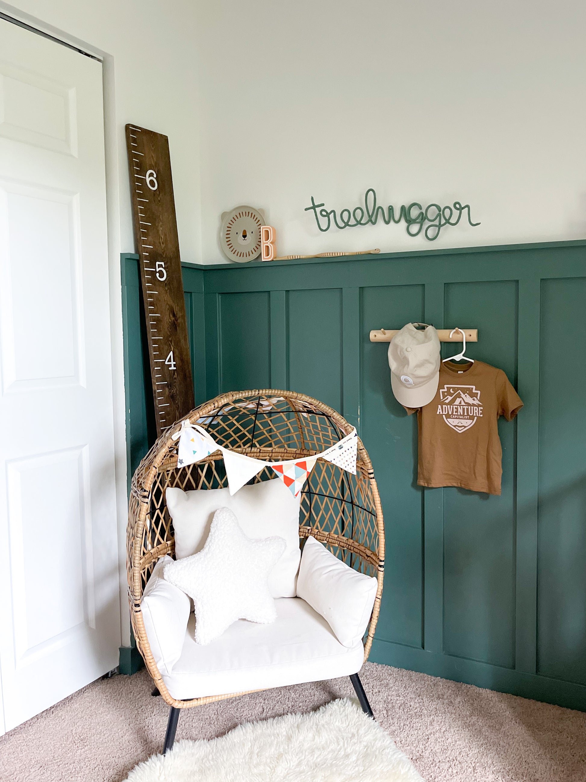 Knitted wire word treehugger hung on a child's bedroom wall. IThe room is nature inspired and outdoorsy.