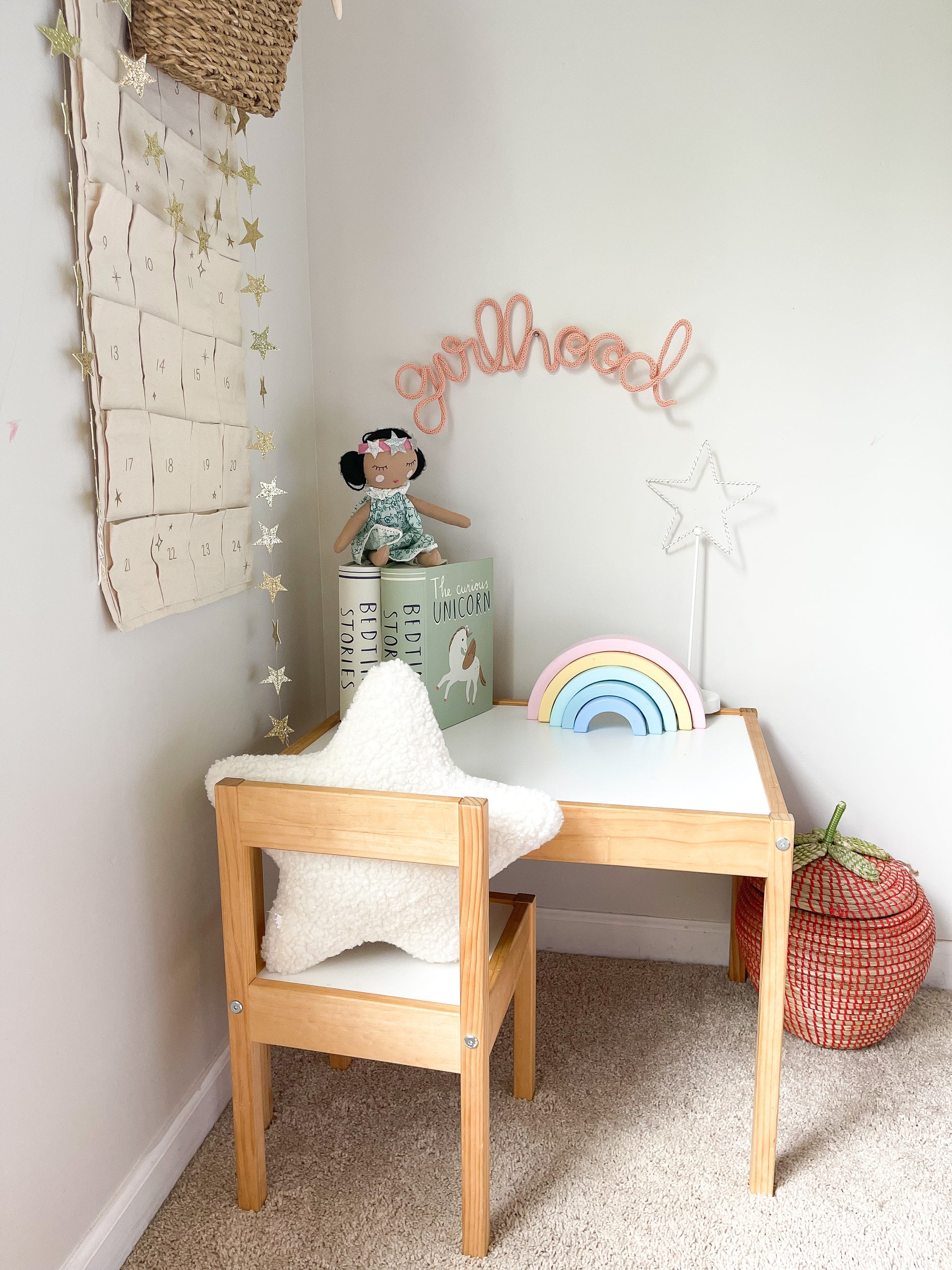 Knitted wire word "girlhood" sign. It's hanging above a girl's desk in her bedroom. 